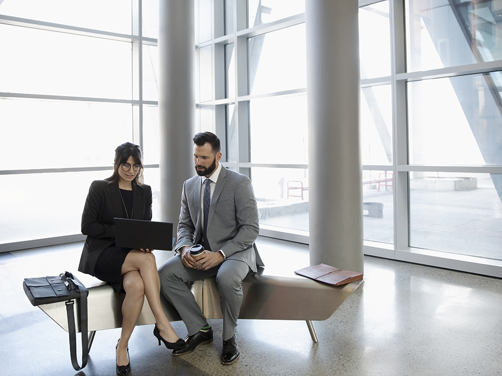 Business people meeting, working at laptop in office lobby