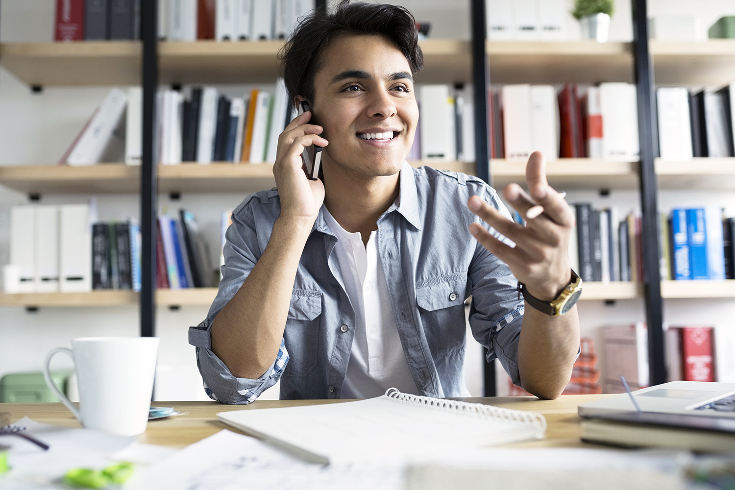 Young businessman talking on cell phone in office