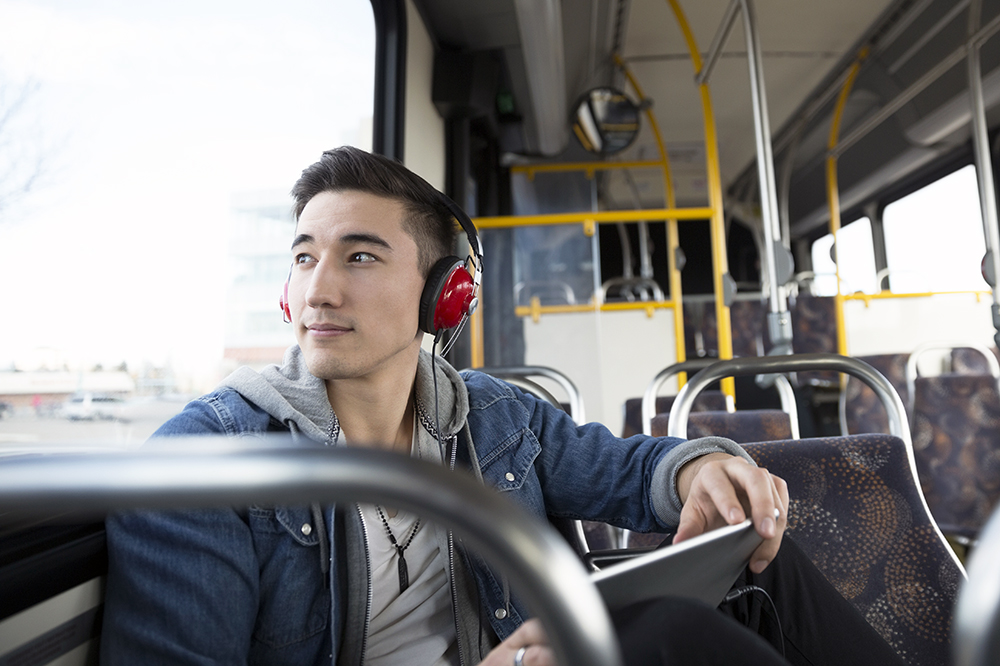Pensive young man riding bus listening music headphones
