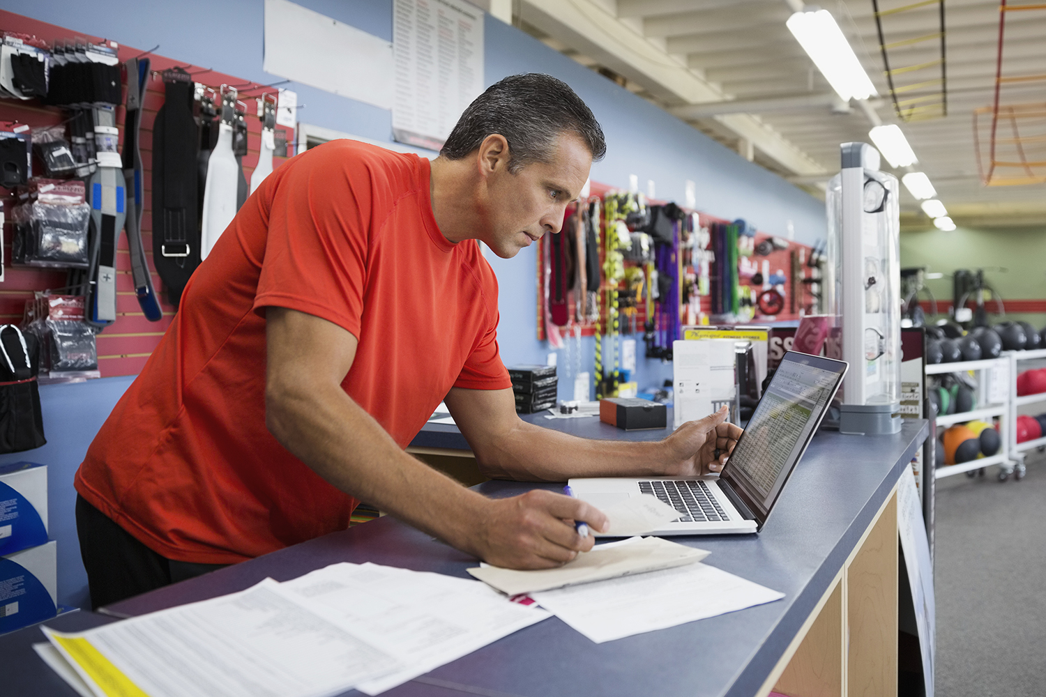 Business owner working at laptop at counter in home gym equipment store