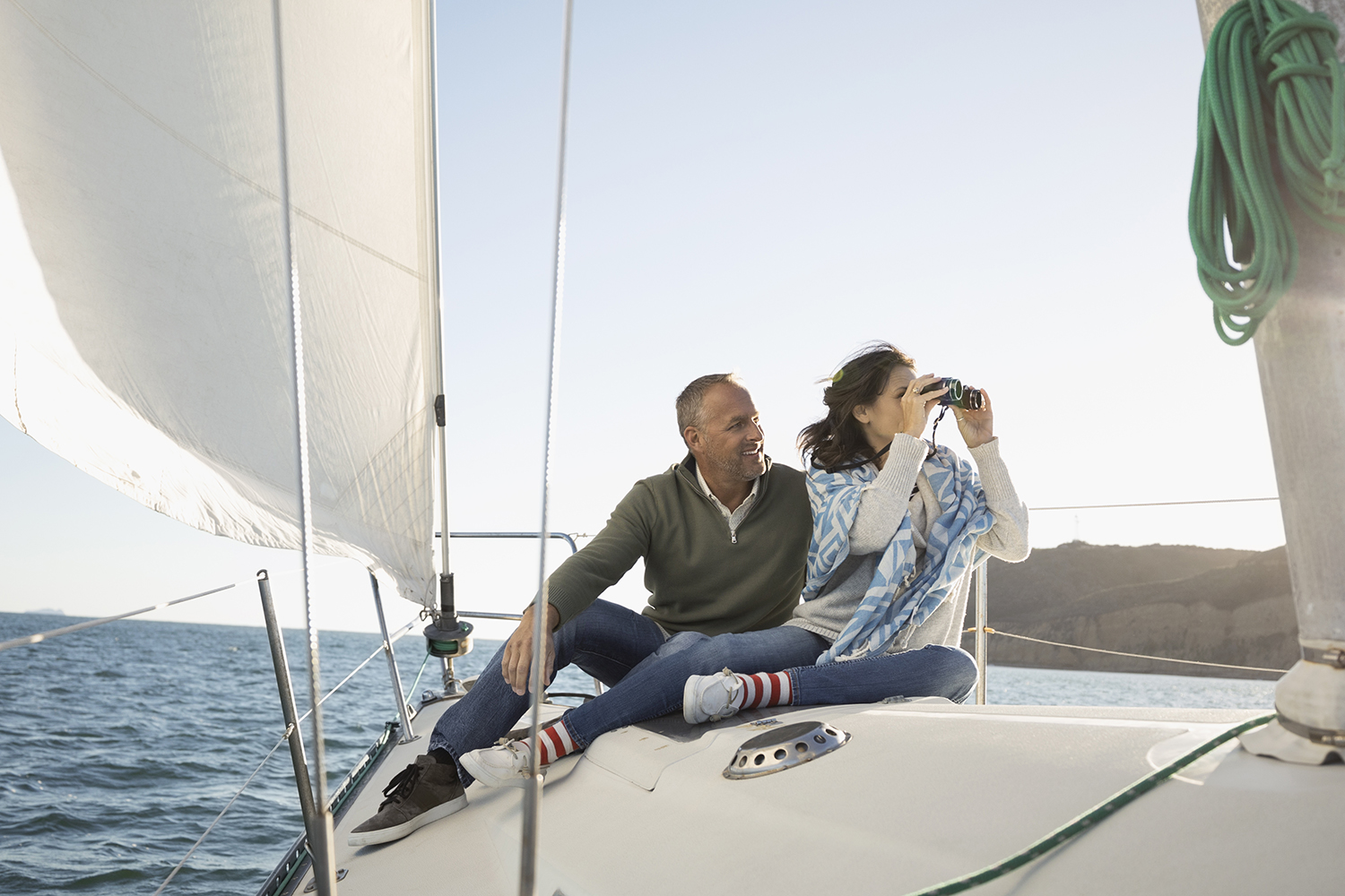 Mature couple using camera on sunny sailboat