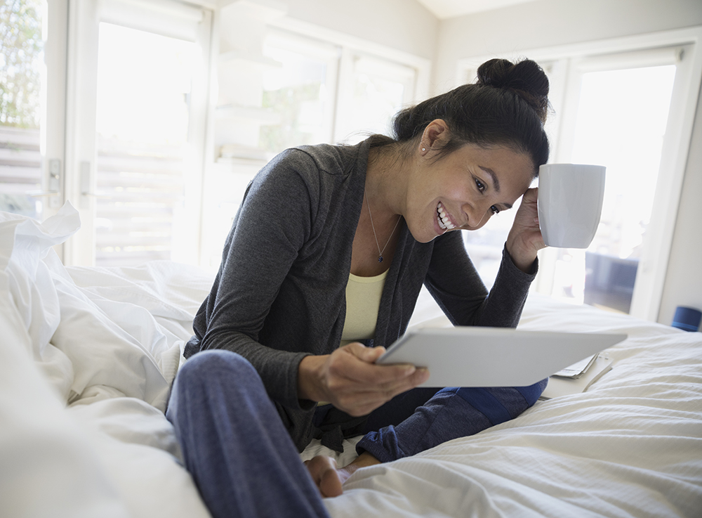 Smiling woman using digital tablet on bed