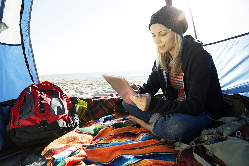Woman using digital tablet in tent on beach