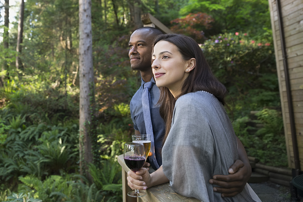 Couple drinking on cabin balcony in woods