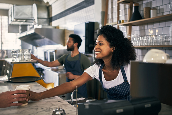 Young woman serving a customer in her coffee shop