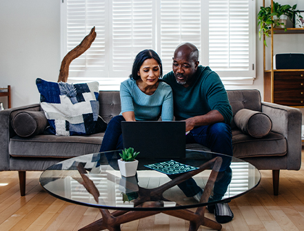 Mature married couple at home on the sofa looking at laptop