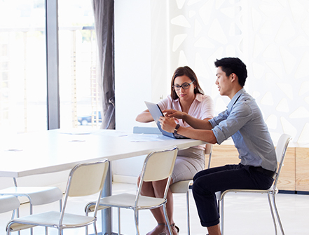 Two people working on a tablet in a meeting room