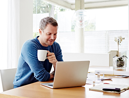 Man working at home using laptop drinking coffee