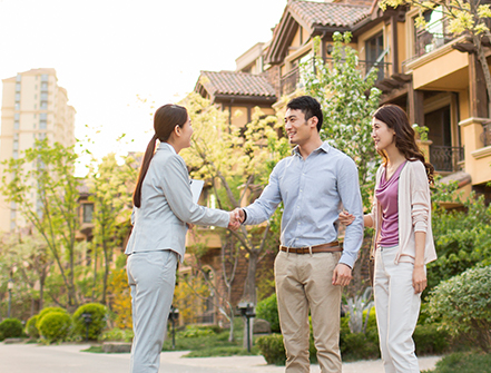 Happy young couple shaking hands with realtor