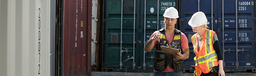 Workers inspecting empty shipping container in industrial container yard