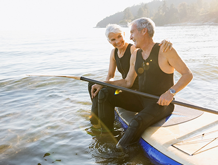 Senior couple on paddle board in ocean.