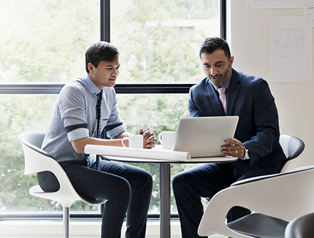 Architects with digital tablet meeting at table in office window.