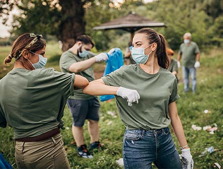 Group of volunteers with surgical masks cleaning nature together.