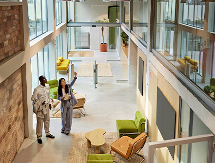 High angle view of female agent standing with male buyer in lobby of modern commercial building for future construction. 