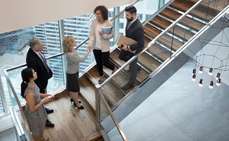员工们在现代化的办公室楼梯握手