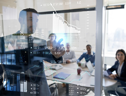 A group of business partners gather inside a meeting room to discuss stocks, investments, and more.