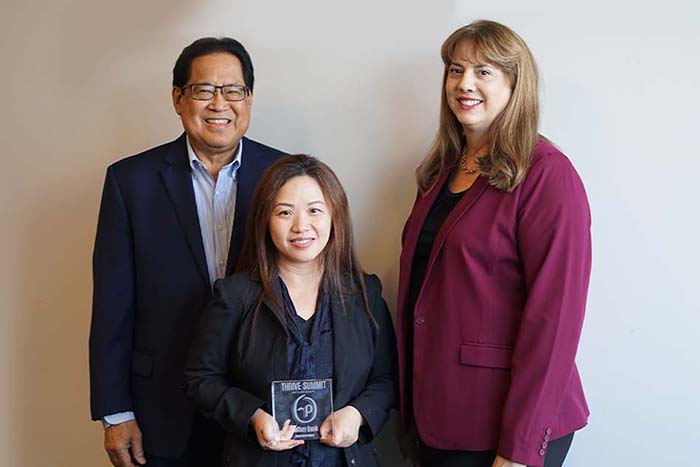 Three executive employees pose with an award from Personify Health in a conference room with a Cathay Bank logo displayed.