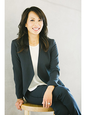 身穿藍色西裝和白色襯衫的高管女商人Ann Kono 在專業工作室中微笑著擺姿勢拍攝公司頭像。