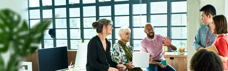 Group of people talking by a window.
