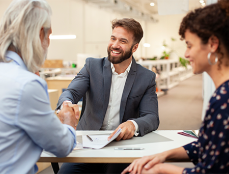 Business professional meeting with clients, shaking hands over documents during a discussion on analyzed business checking solutions.