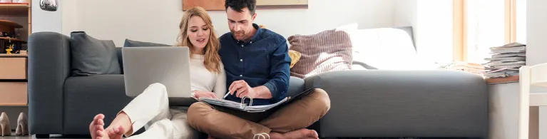 Couple with laptop looking at paperwork.