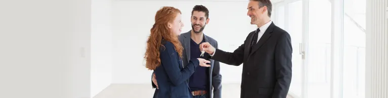 Estate agent handing over keys to young couple.