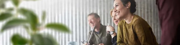 A young professional leans over a conference table with colleagues discussing treasury management services. 