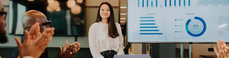 A young woman presents asset-based lending options to a meeting room full of people.