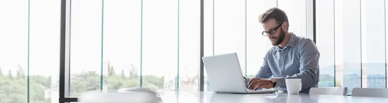 Man using laptop sitting at conference table in office