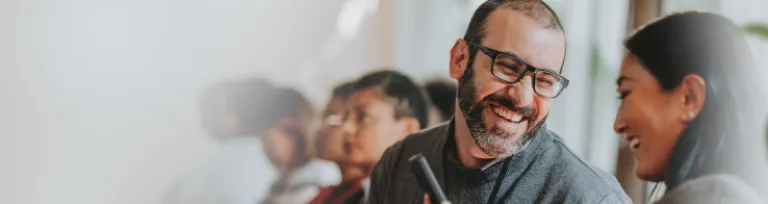 Business woman shows smartphone during conference to the man next to her