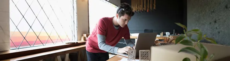 Focused male designer working at laptop in workshop