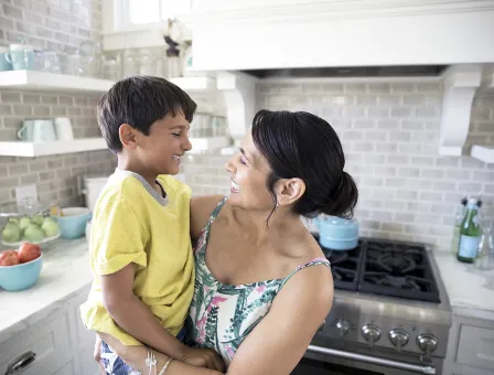 Smiling mother holding son in kitchen