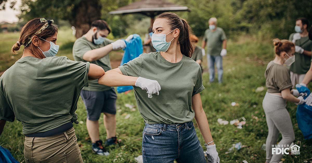 Group of volunteers with surgical masks cleaning nature together.