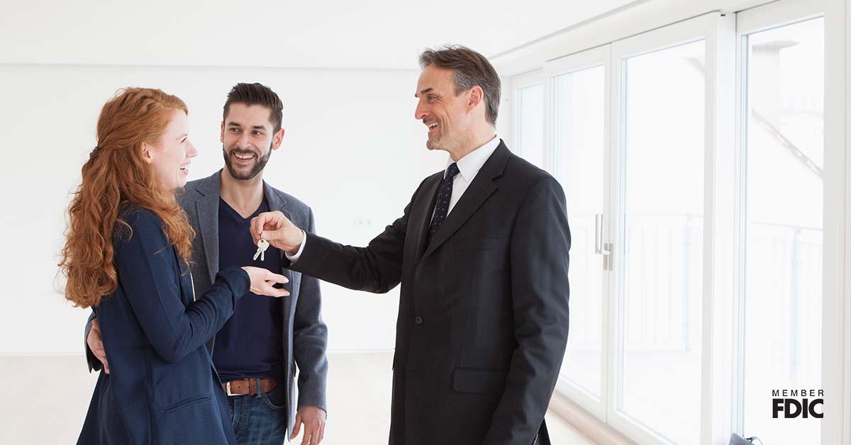 Estate agent handing over keys to young couple.