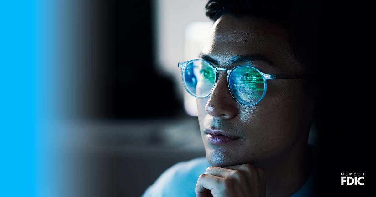 There is a close-up of a young male’s face wearing glasses, which reflects his on-screen activity from an electronic device.