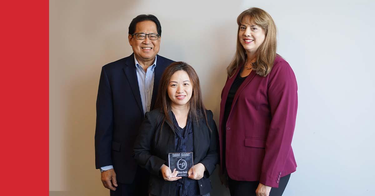 Three executive employees pose with an award from Personify Health in a conference room with a Cathay Bank logo displayed.