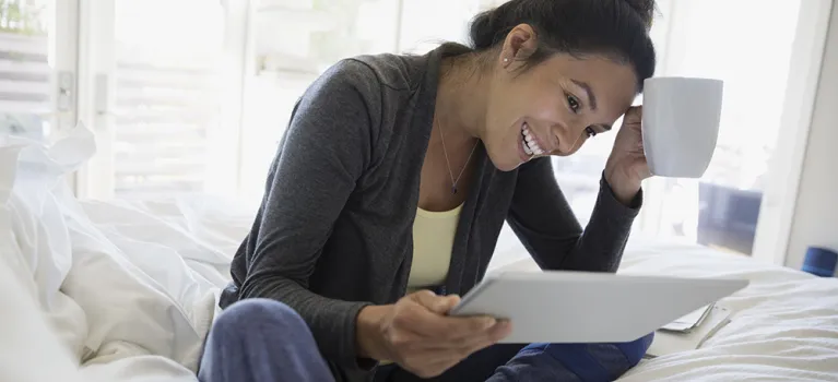 Smiling woman using digital tablet on bed