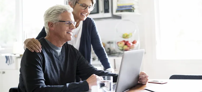Senior couple using laptop at kitchen table