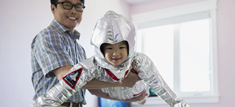 Portrait of grandfather flying granddaughter in astronaut costume