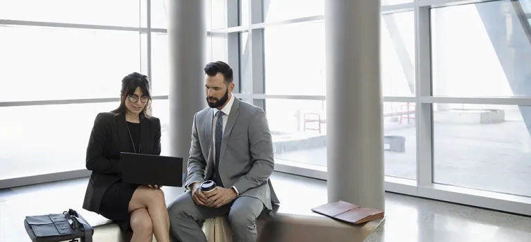 Business people meeting, working at laptop in office lobby