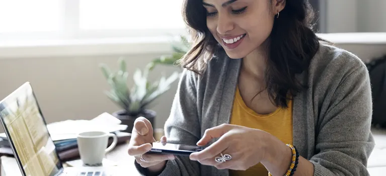 Young woman depositing check online with camera phone in living room
