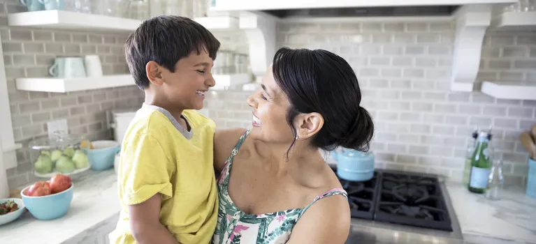 Smiling mother holding son in kitchen