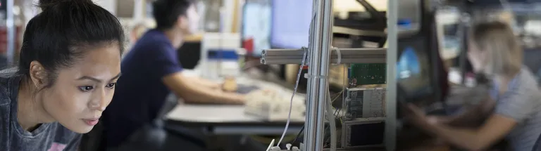 Focused female engineer working at laptop in workshop