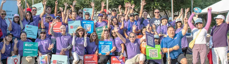 A group of Cathay Bank team members in purple t-shirts gather around the informational booth at the annual Walk for Hope fundraising event at the City of Hope facility in Duarte, California.