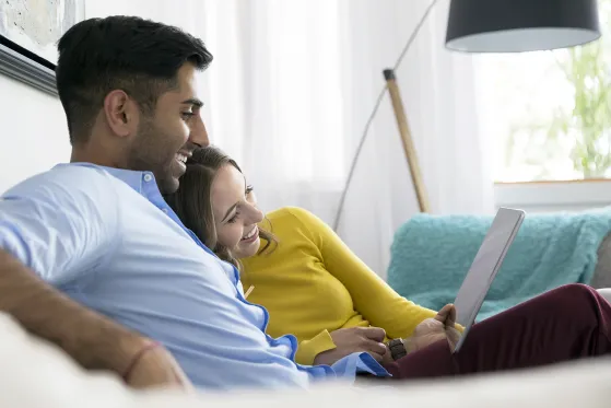 Young couple relaxing using digital tablet on living room sofa