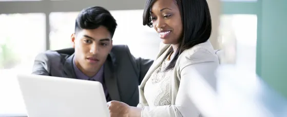 Businesswoman sharing laptop with male colleague in office