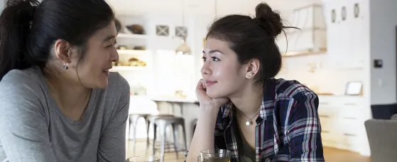 Mother and teenage daughter holding hands drinking tea