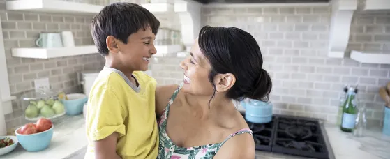 Smiling mother holding son in kitchen