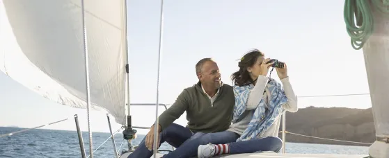 Mature couple using camera on sunny sailboat