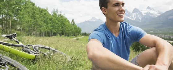 Man with mountain bike sitting in grass
